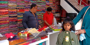 DISTRICT KATNI, INDIA - 18 Eylül 2019: Hintli bir esnaf Hindistan festivali pazarında çocuk giysileri satıyor.