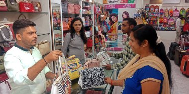 DISTRICT KATNI, INDIA - 18 EYLÜL 2019: Hintli bir bayan esnaf çantasını çanta dükkanındaki müşteriye satmak için kadınlara sunuyor.