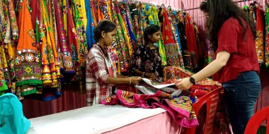 DISTRICT KATNI, INDIA - 22 EYLÜL 2019: 2 Hintli satıcı kız şehir kızına lehenga desenleri gösteriyor.