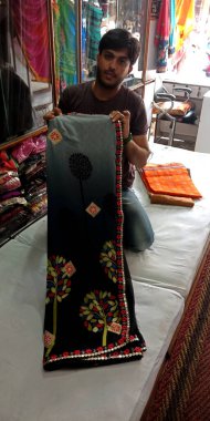 DISTRICT KATNI, Hindistan - 22 Eylül 2019: Güzel Sari kıyafetlerini yerel marketteki geleneksel kıyafet mağazasına gösteren Hintli bir esnaf.