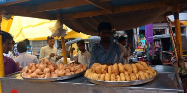 DISTRICT KATNI, INDIA - 24 Eylül 2019: Bir Hint gıda satıcısı marketin caddesinde taze Vada samosa sergiledi.