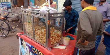 DISTRICT KATNI, INDIA - 13 Ekim 2019: Sokak arabası dükkanındaki müşteriye panipuri satan Hintli bir çocuk.