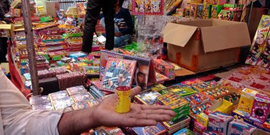 DISTRICT KATNI, INDIA - 15 Ekim 2019: Geleneksel pazarda alacakaranlık festivalinde müşteriye Diwali Krakerleri sunan Hintli bir köy esnafı.