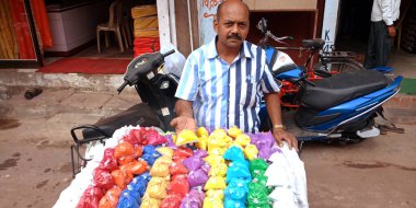 DISTRICT KATNI, INDIA - 19 Ekim 2019: Hindu geleneksel diwali festivali sırasında yerel sokak şehir pazarında rangoli renkleri satan Asyalı yetişkin bir esnaf.