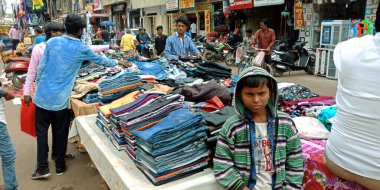 DISTRICT KATNI, INDIA - 19 Ekim 2019: Hindu geleneksel diwali festivali sırasında yerel sokak şehir pazarında elbise satan Asyalı küçük çocuk.