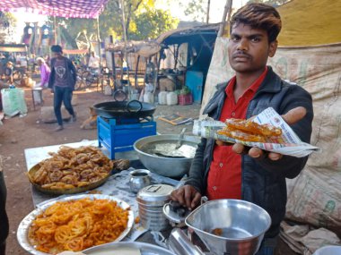 DISTRICT KATNI, INDIA - Şubat 02, 2020: Köyün pazar festivali sezonunda faytoncuda geleneksel Jalebi tatlısı sunan Hintli fakir bir çocuk.