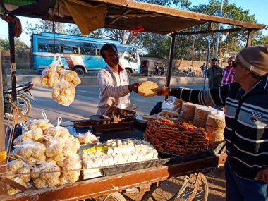 DISTRICT KATNI, INDIA - Şubat 02, 2020: Köy pazarı festivali sezonunda yaşlı bir adama geleneksel tatlı veren Asyalı bir adam.