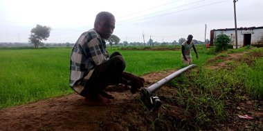 DISTRICT KATNI, INDIA - Ağustos 03, 2019: Hint köyü çiftçileri açık hava ortamında yeşil tarım alanı etrafında sulama boruları kuruyorlar.