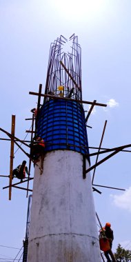 DISTRICT KATNI, INDIA - 16 Temmuz 2019: Hintli yol inşaat işçisi gökyüzü arka planında köprü oluşturmak için çimento direğine tırmanıyor.