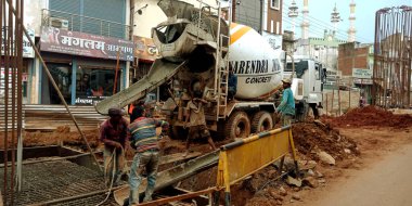 DİSTRİK KATNI, INDIA - 07 Ağustos 2019: Hintli yol yapım işçileri cadde üzerindeki mikser kamyonundan inşaat malzemeleri üretiyorlar.