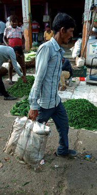 DİSTRİK KATNI, INDIA - 12 Ağustos 2019: Marketten taze yeşil tarım ürünleri aldıktan sonra yolda sebze torbası taşıyan Asyalı fakir bir adam.