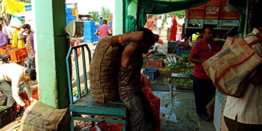 DİSTRİK KATNI, INDIA - 12 Ağustos 2019: Asyalı bir adam pazardan taze yeşil tarım ürünleri aldıktan sonra manüel çabalarla sebze çuvalı taşıdı.