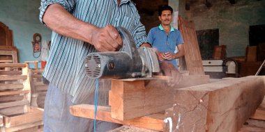 DISTRICT KATNI, INDIA - 16 Eylül 2019: Asyalı ahşap işçisi Saw Mill şantiyesindeki elektrik makinesinin ahşap kütüklerini bitiriyor.