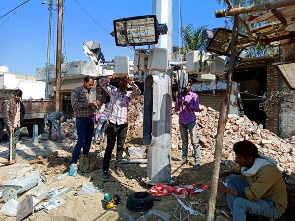 DISTRICT KATNI, INDIA - 2009 HAZİRAN 2020: Hindistan hükümetinin elektrik hattı çalışanları alüminyum direkte sokak lambalarını birleştiriyor.
