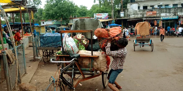 DİSTRİK KATNI, INDIA - 12 AĞUSTOS 2019: Hint triportör sürücüsü sebze poşetlerini kendi çabalarıyla yola koyuyor.