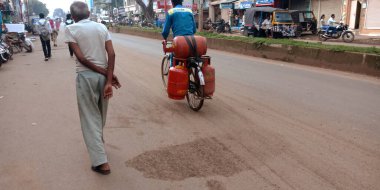 DISTRICT KATNI, INDIA - 18 Eylül 2019: LPG gaz silindirini açık hava ortamında yol kenarına taşıyan Hintli bir adam.