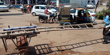 DISTRICT KATNI, INDIA - 18 EYLÜL 2019: Bambu merdivenlerini açık hava ortamında yol kenarına taşıyan Hintli bir elektrik hattı çalışanı.