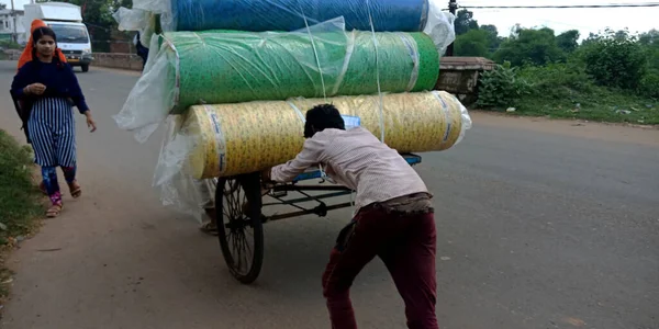 DISTRICT KATNI, INDIA - 18 Eylül 2019: Yerli fakir bir işçi yük arabalarını açık hava ortamında yol kenarına itiyor.