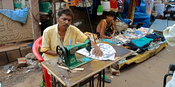 DISTRICT KATNI, INDIA - SEPTEMBER 18, 2019: An indian poor street tailor stitching cloth from sewing machine on road side at outdoor environment.