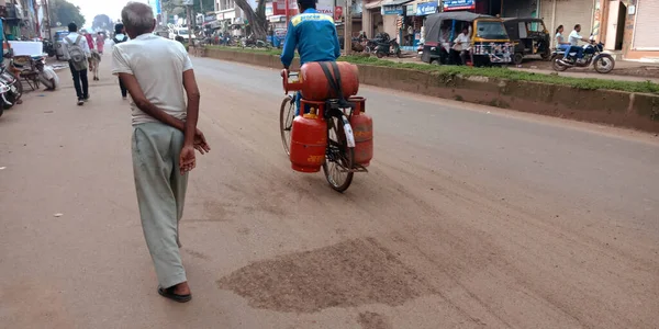 DISTRICT KATNI, INDIA - 18 Eylül 2019: LPG gaz silindirini açık hava ortamında yol kenarına taşıyan Hintli bir adam.