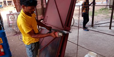 DISTRICT KATNI, INDIA - 06 Ekim 2019: Bir Hintli demirci atölyenin kapısını açmak için elektrik kesici kullanıyor.