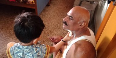 DİSTRİK KATNI, Hindistan - 06 Ekim 2019: Hintli şirin bir çocuk dedesini evinde tıraş ediyor.