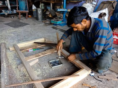 DISTRICT KATNI, INDIA - 09 ARALIK 2019: Otomobil atölyesindeki ahşap yapıdan kamyon iskeleti yapan Hintli bir tamirci.