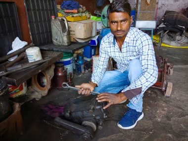 DISTRICT KATNI, INDIA - 09 ARALIK 2019: Otomobil atölyesindeki tornavidanın motoru tamir eden Hintli bir tamirci.