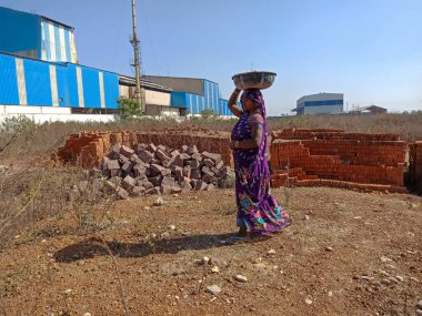 DİSTRİK KATNI, INDIA - 13 Aralık 2019: İnşaat alanında inşaat malzemeleri taşıyan Hintli bir köylü kadın işçi.