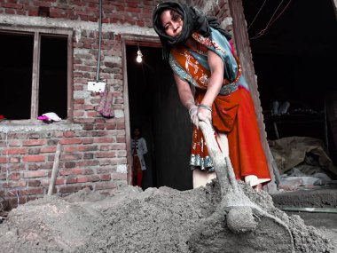 DISTRICT KATNI, INDIA - 18 Aralık 2019: Hintli bir köylü kadın işçi ev inşaatı sahasında maça yapı malzemesi üretiyor.