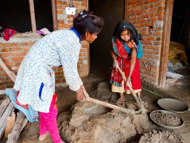 DISTRICT KATNI, INDIA - 18 Aralık 2019: Ev inşaatı sahasında maça yapı malzemelerini karıştıran iki Hintli kadın işçi.