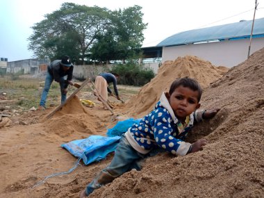 DISTRICT KATNI, INDIA - 18 Aralık 2019: İnşa alanındaki kum deposuna tırmanan Hintli bir işçi köyü çocuğu.