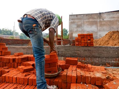 DİSTRİK KATNI, Hindistan - 18 Aralık 2019: Hintli bir erkek işçi ev yapımı için tuğla topluyor.