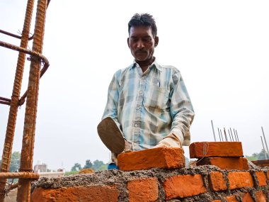 DISTRICT KATNI, INDIA - 18 ARALIK 2019: Hindistan 'da bir köy inşaatı hatası gökyüzü arka planında tuğla duvar yapımı için çimento malzemesi onarıyor.