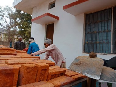 DISTRICT KATNI, INDIA - 21 ARALIK 2019: Dışarıdaki arka planda yüklü traktörden tuğla toplayan Hintli köy işçisi.