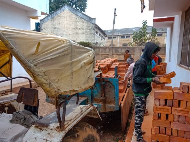 DISTRICT KATNI, INDIA - 21 ARALIK 2019: Bir Hintli köy çalışanı dış arkaplanda traktör malzemesi boşaltımı sırasında tuğla düzenliyor.