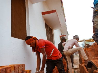 DISTRICT KATNI, INDIA - 21 ARALIK 2019: Yerli köylü işçi grubu, yüklenen traktörün dış planda yaptığı çalışmalar sırasında tuğla düzenliyor.