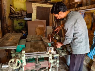 DISTRICT KATNI, INDIA - HAZİRAN 08, 2020: Bir Hintli marangoz atölye odun kesmek için makine sapı ayarlama.