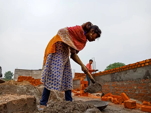DISTRICT KATNI, INDIA - 18 Aralık 2019: Yerli köyünde genç bir kadın işçi ev inşaatında maça ile güçlendirilmiş yapı malzemesi yapıyor.