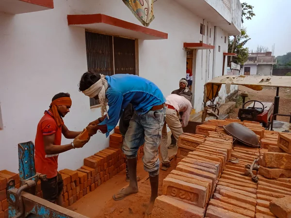 DISTRICT KATNI, INDIA - 21 ARALIK 2019: Hintli köy çalışanı açık arka planda yüklü traktörden tuğla indiriyor.