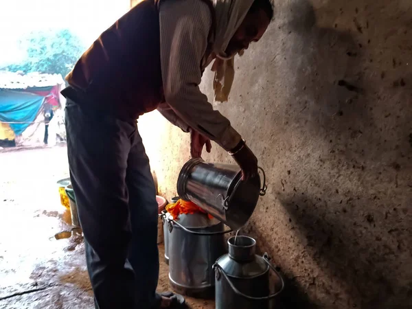 DISTRICT KATNI, INDIA - HAZİRAN 04, 2020: Yerel süt çiftliğinde süt toplayan bir mandıra çiftçisi, bir Hint tarım sahnesi.