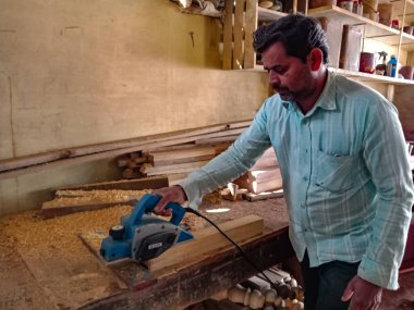 DISTRICT KATNI, INDIA - 08 Ocak 2020: Atölyedeki elektrik kesicisinden odun kesen Hintli bir erkek oduncu.