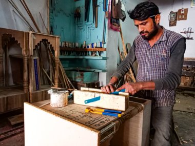 DISTRICT KATNI, INDIA - 08 HAZİRAN 2020: Bir Hintli ahşap sanatçı atölyedeki bıçaktan odun kesiyor.
