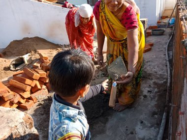 DİSTRİK KATNI, Hindistan - 13 HAZİRAN 2020: İnşaat sırasında kadın işçilere kürek veren Hintli küçük bir çocuk.