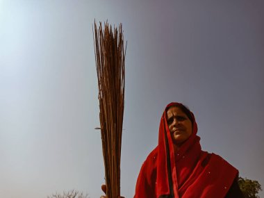 DİSTRİK KATNI, INDIA - 18 HAZİRAN 2020: Hintli bir köylü kadın doğal arka planda süpürge tutuyordu.