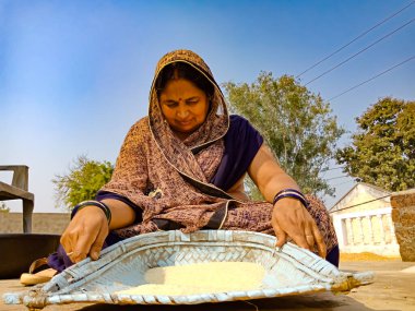 DİSTRİK KATNI, Hindistan - 18 HAZİRAN 2020: Asyalı bir köy kadını pirinç tohumlarını doğal arka planda temizliyor.