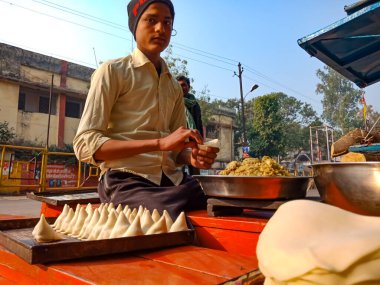 DİSTRİK KATNI, Hindistan - 18 HAZİRAN 2020: Caddenin köşesinde samosa yapan Hintli bir çocuk.