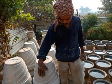 DISTRICT KATNI, INDIA - 18 HAZİRAN 2020: Asyalı bir sanatçı doğal arka plandaki açık alan atölyesinin çimento tenceresini bitirdi.
