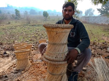DISTRICT KATNI, INDIA - 18 HAZİRAN 2020: Doğal arka planda açık alan atölyesinde kuru çim sunan bir Hintli köy adamı.