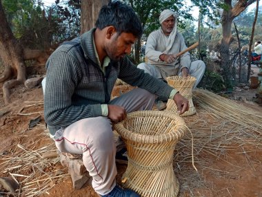 DISTRICT KATNI, INDIA - 18 HAZİRAN 2020: Doğal arka planda açık alan atölyesinde kuru çim üreten Hintli genç bir adam.